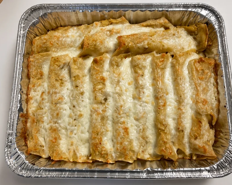 Tray of baked enchiladas topped with melted cheese from Tres Marias Mexican Food Market in Calgary, AB